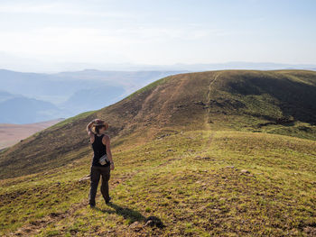 Full length of young woman hiking in drakensberg mountains at highmoor nature reserve, south africa