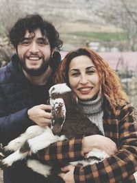 Portrait of smiling couple with kid goat