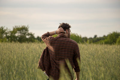 Rear view of young man walking on field