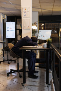 Rear view of woman using laptop at home