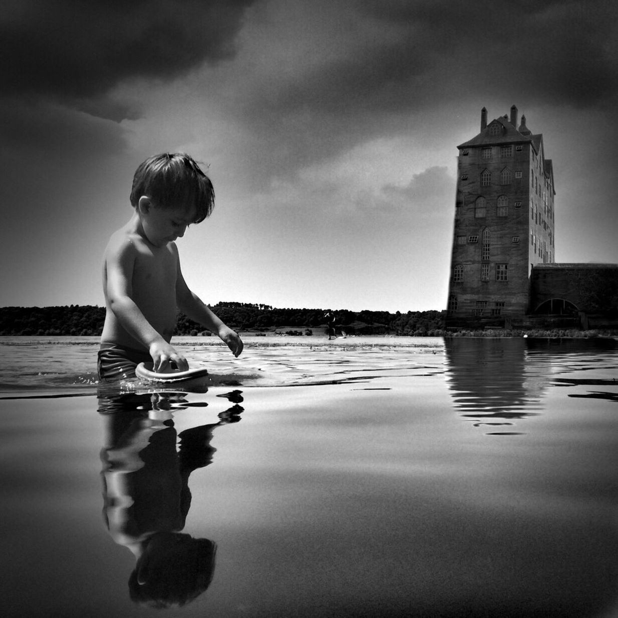 water, lifestyles, leisure activity, built structure, sky, architecture, sea, building exterior, full length, standing, cloud - sky, casual clothing, boys, reflection, waterfront, beach, childhood