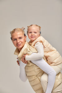 Portrait of smiling mother and daughter against white background