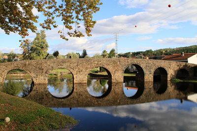 Arch bridge over river against sky