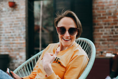 Beautiful young woman with short blond hair in casual clothing sitting and smiling.