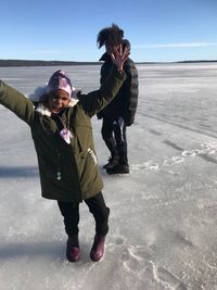 Full length of brother and sister standing on frozen lake