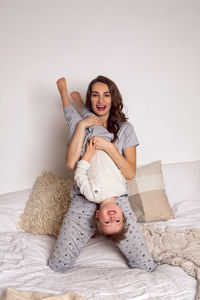 Mom and son playing on a big white bed in gray pajamas