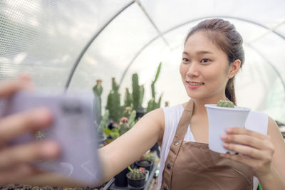 Portrait of smiling woman holding mobile phone in city