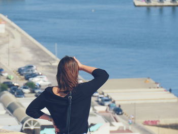 Rear view of woman standing by sea against sky