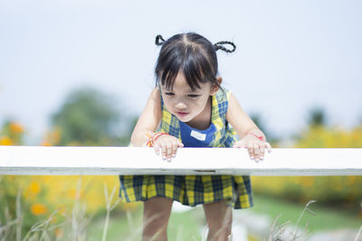 Side view of boy looking away while sitting on railing