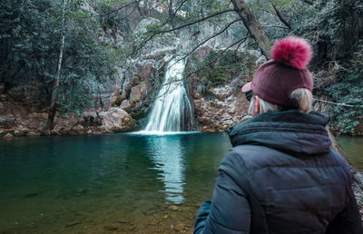 Rear view of woman in river amidst trees in forest