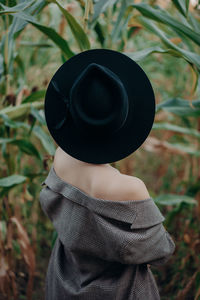 Rear view of woman wearing hat standing amidst plants