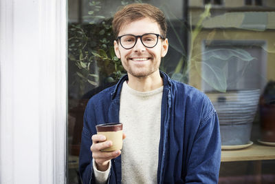 Portrait of smiling man having coffee outside art studio
