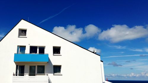 Low angle view of building against cloudy blue sky on sunny day