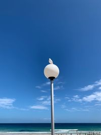 Low angle view of street light by sea against sky