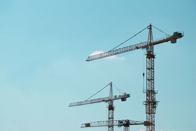 Low angle view of crane against clear blue sky