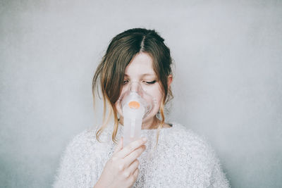 Portrait of a woman with eyes closed against wall