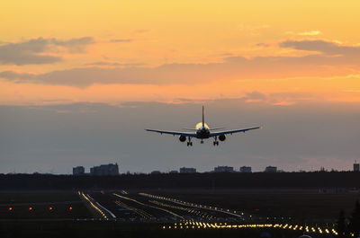 Airplane flying against sky during sunset