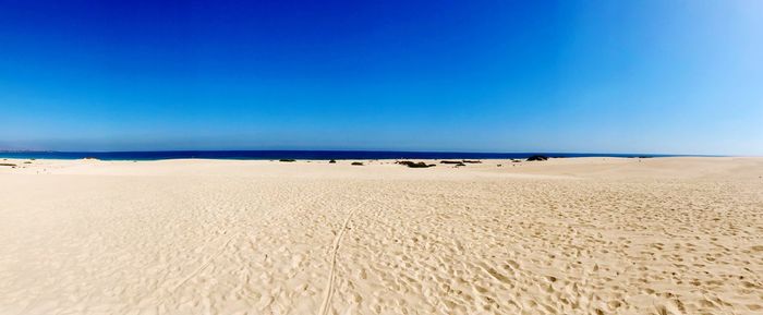 Scenic view of beach against clear blue sky