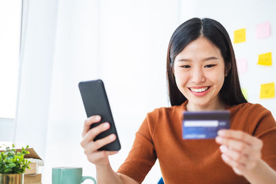 Portrait of smiling young woman using mobile phone