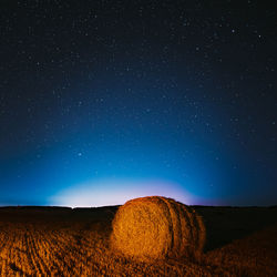 Hay bales on field against sky at night