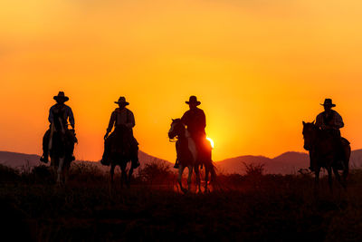 Silhouette people on field against sky during sunset