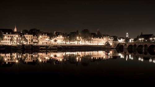 Reflection of illuminated buildings in lake against sky at night