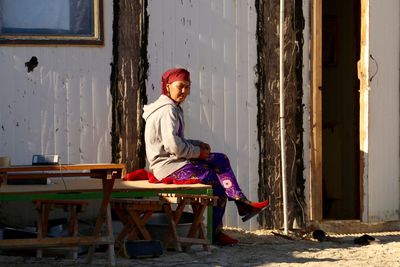 Portrait of woman sitting on table against building