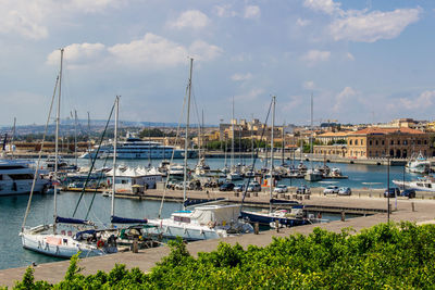 Sailboats moored at harbor against sky