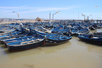 Sailboats moored in sea against sky