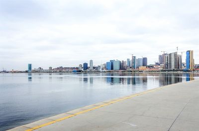 Sea by cityscape against sky