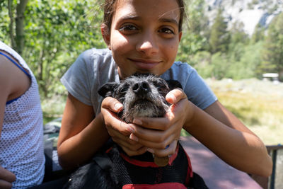Tween girl holds dog's face and smiles for the camera