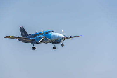 Low angle view of airplane flying against clear blue sky