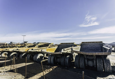 Large off road dump trucks lined up awaiting their next assignment with blue sky in background