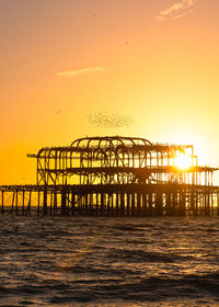 Silhouette pier over sea against sky during sunset