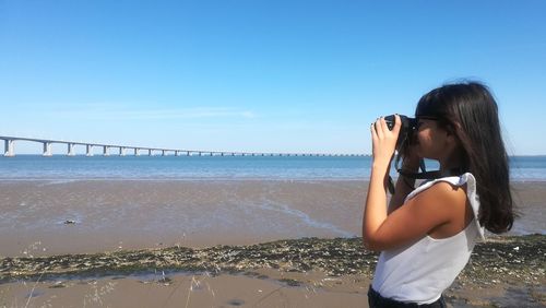 Woman standing at beach against sky