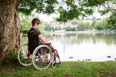 Man sitting by lake against trees