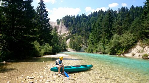 Man sitting on canoe at isar riverbank