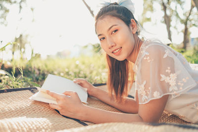 Portrait of young woman reading book outdoors