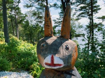 Wooden sculpture of a smiling rabbit in the forest, on a sunny day