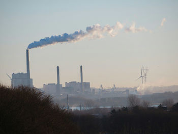 Smoke emitting from factory against sky