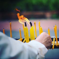 Cropped hand of person burning yellow candles at church