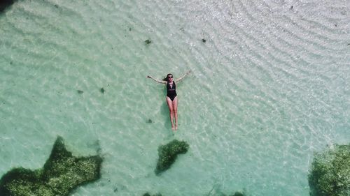 Aerial view of woman floating on water in sea