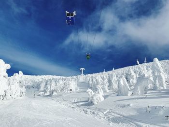 Ski lift over snow covered mountains against sky