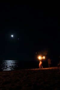 People at beach against sky at night