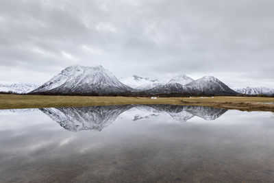 Scenic view of lake by snowcapped mountains against sky