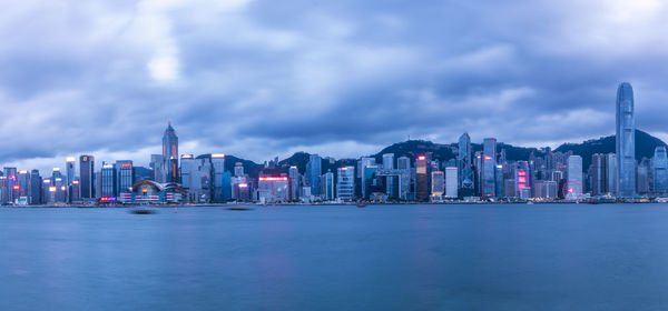 Sea by modern buildings against sky in city