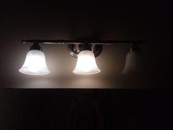 Low angle view of illuminated light bulb hanging on wall