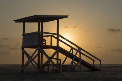 Lifeguard hut at beach against sky during sunset