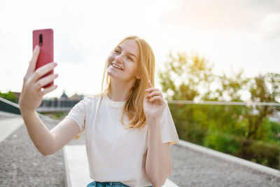 Portrait of young woman standing against trees