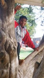 Portrait of smiling man standing on tree trunk